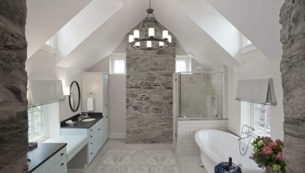 Farm House bathroom with clawfoot tub, stone wall and cathedral ceiling